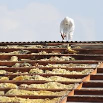 Asbestos worker on roof wearing protective clothing and respirator