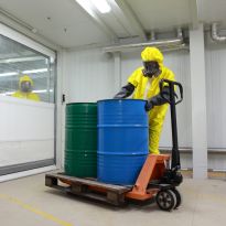 Worker wearing PPE handling hazardous waste container