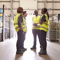 Four employees discussing safety in a warehouse