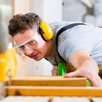 Worker wearing ear hearing protection while cutting wood on a table saw