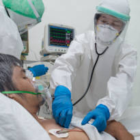 Healthcare practitioner wearing PPE head, body, hand, face protection, and mask respirator. 