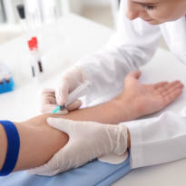 Healthcare worker drawing blood from the arm of a patient