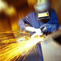 Worker in PPE grinding metal