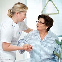 Healthcare worker assisting patient out of bed