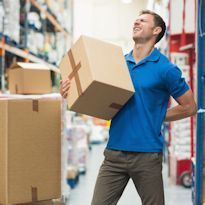 Worker in warehouse hold box showing lower back pain