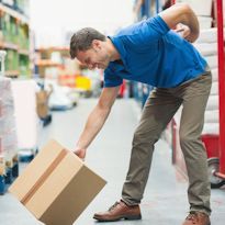 Warehouse worker bent over to pick up box and experiencing lower back pain