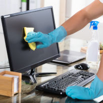 Worker wearing PPE cleaning computer screen