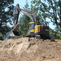 Excavator removing soil from a large excavation