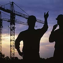 Two construction managers discussing worksite cranes